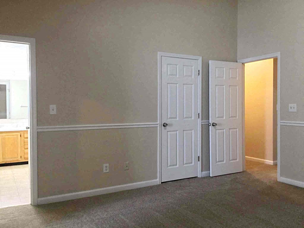 Three white doors are in a hallway.