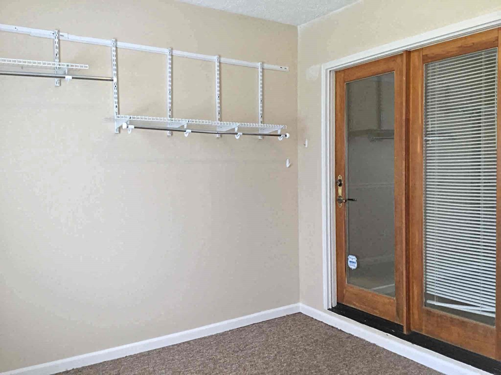 A room with a white wall and a brown door.