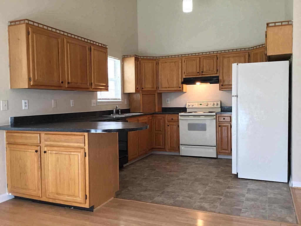 A kitchen with wooden cabinets and a black countertop.