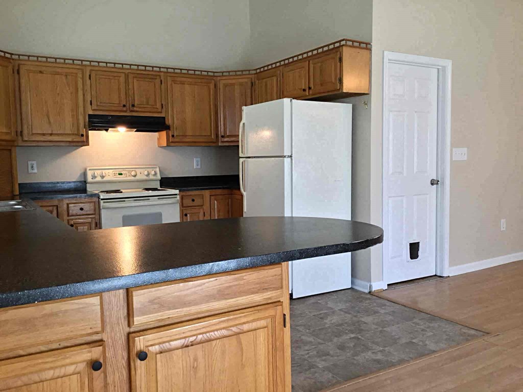A kitchen with wooden cabinets and a black countertop.