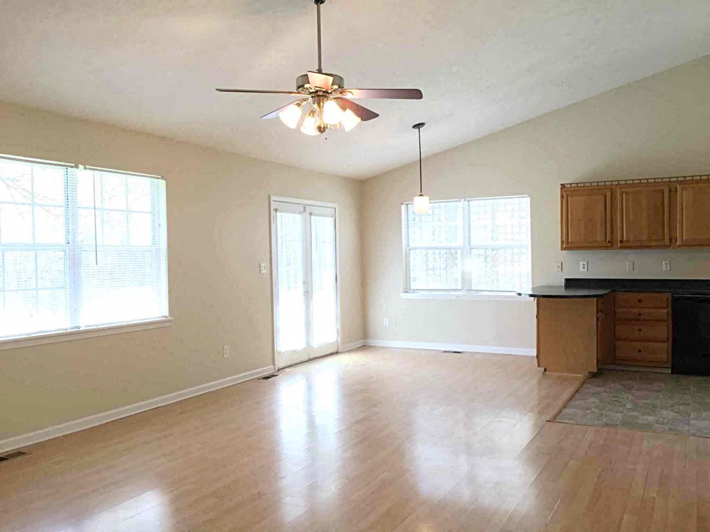 A room with a ceiling fan and wooden floors.