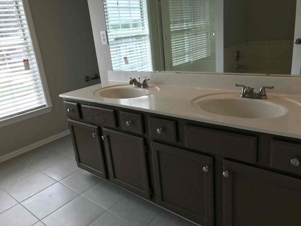 A bathroom with two sinks and brown cabinets.