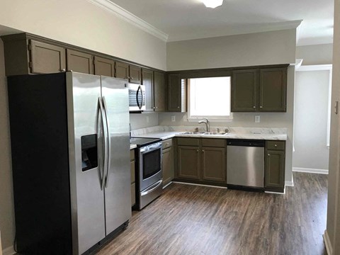 A kitchen with a black refrigerator, stainless steel oven, and wooden cabinets.
