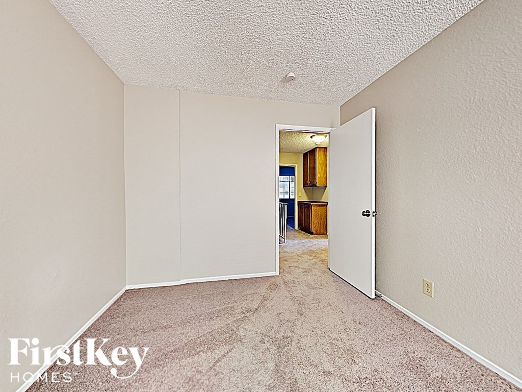 a bedroom with a carpeted floor and a door to a kitchen