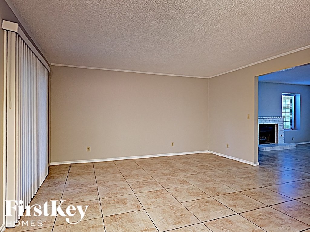 an empty living room with tile flooring and a fireplace