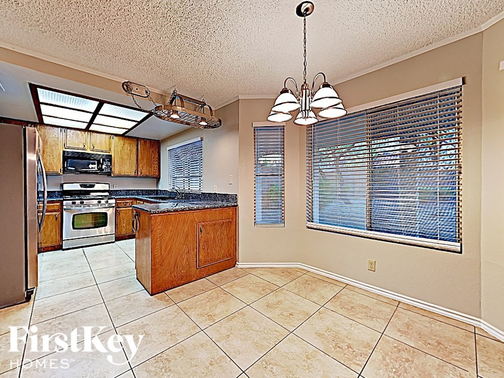 an empty kitchen with a large window and a refrigerator