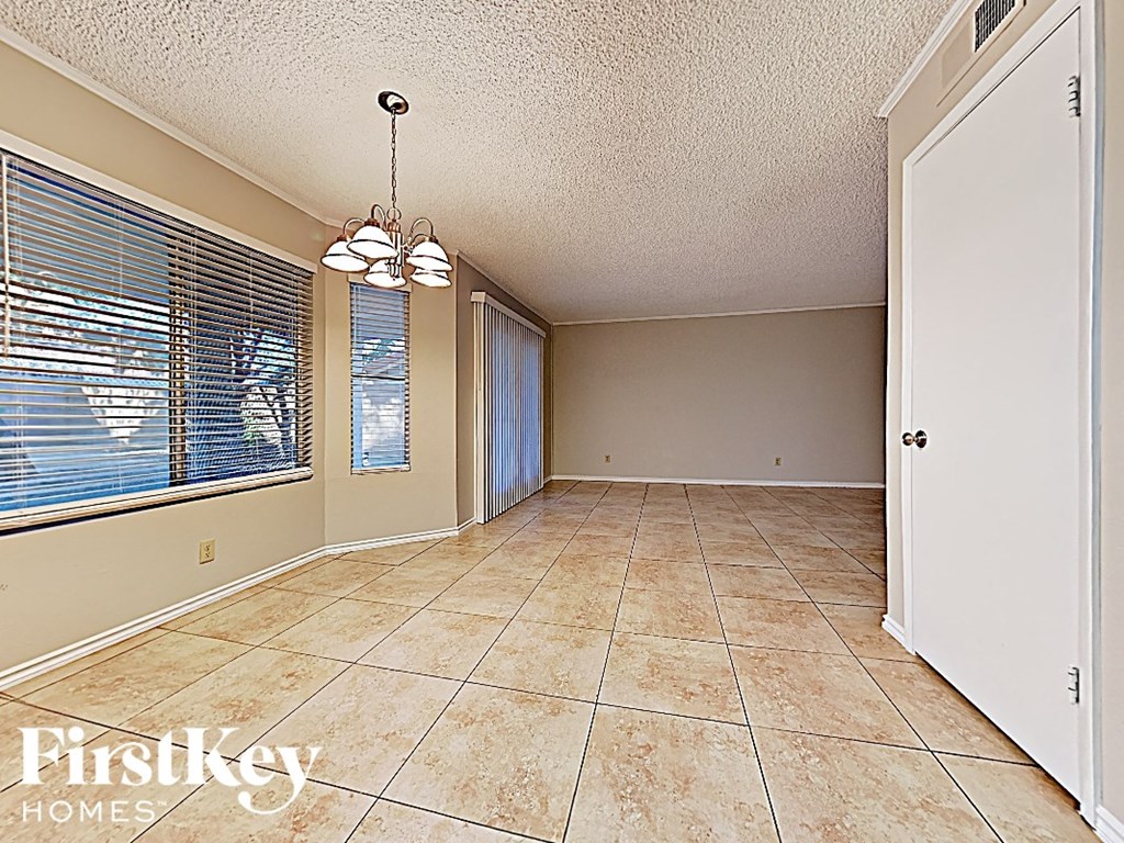 an empty living room with a large window and tiled floor