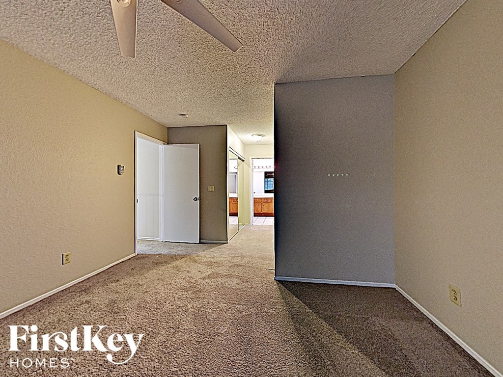 the living room of an empty house with a door to the kitchen