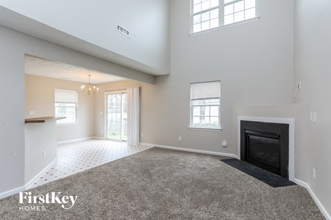 A spacious living room with a fireplace and a carpeted floor.