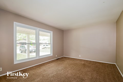 an empty bedroom with a large window and carpet