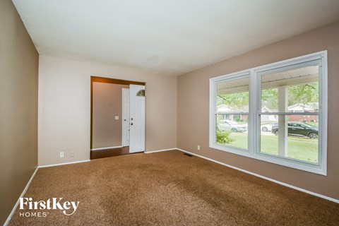 an empty living room with a large window and carpet