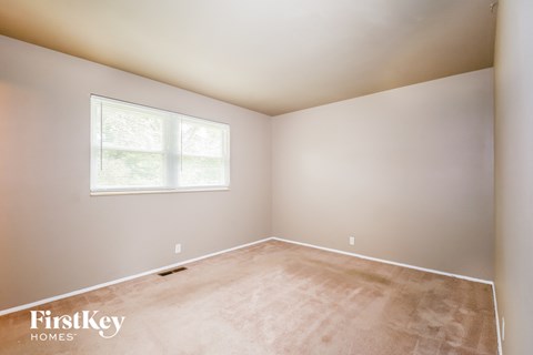 a bedroom with a large window and a carpeted floor