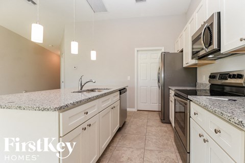 a white kitchen with granite counter tops and stainless steel appliances