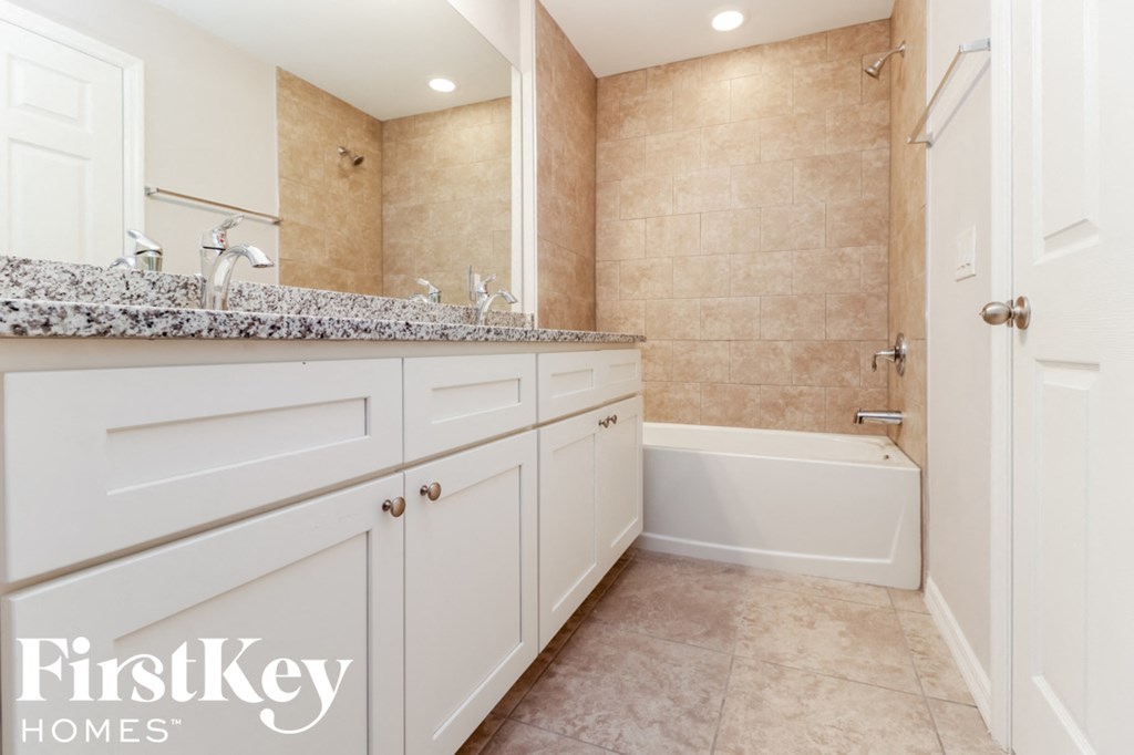 a bathroom with white cabinets and a sink and a tub