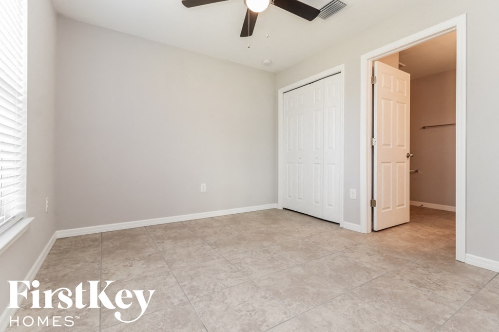 an empty living room with a closet and a ceiling fan