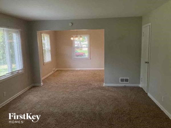 A room with a carpeted floor and a window with blinds.
