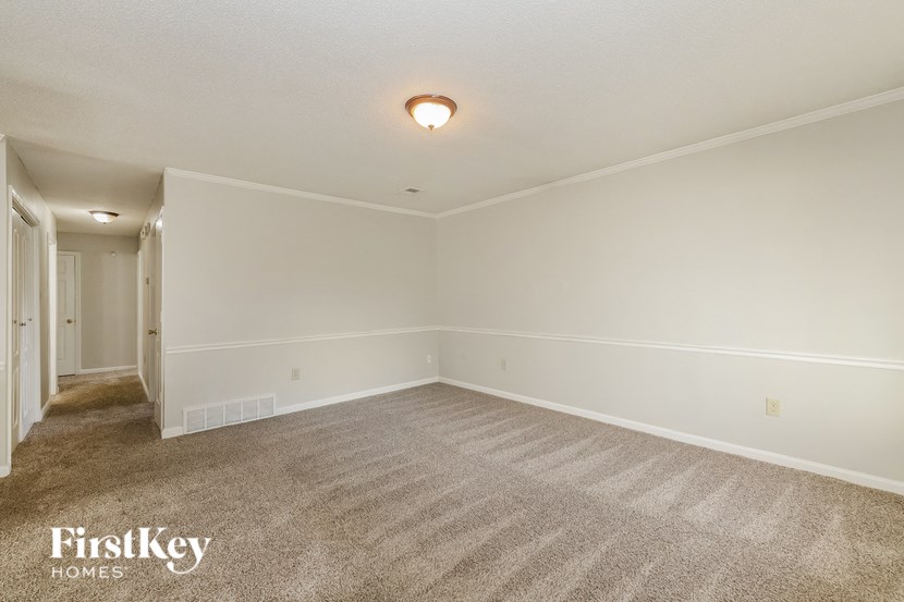 a spacious living room with carpet and white walls