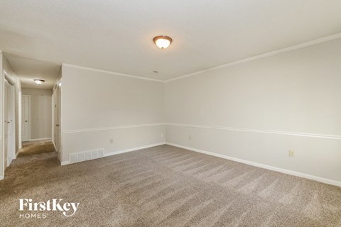 a spacious living room with carpet and white walls
