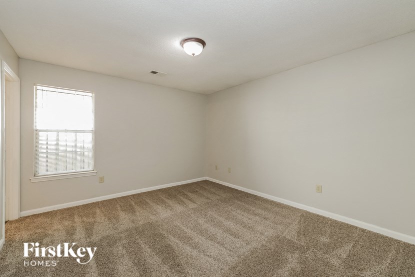 the spacious living room with carpeting and a window