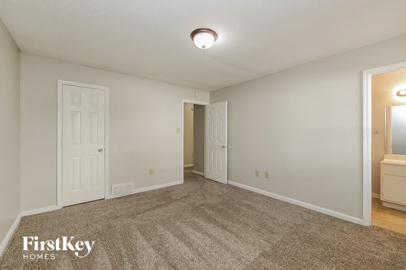 a spacious living room with carpet and white doors
