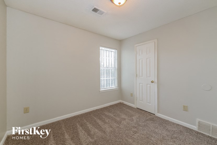 a bedroom with white walls and carpet and a white door