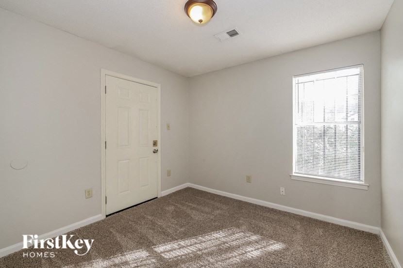a bedroom with a white door and carpet and a window