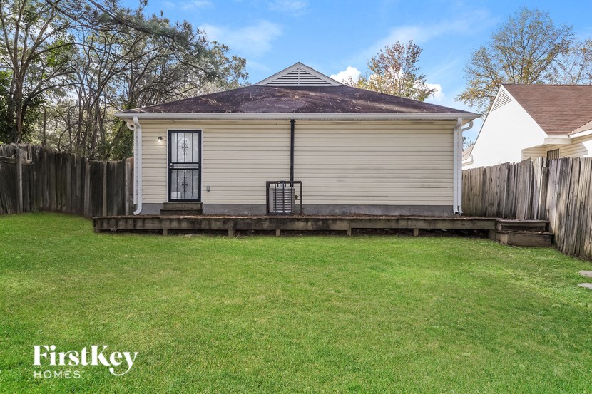 the back of a small house with a lawn and a fence