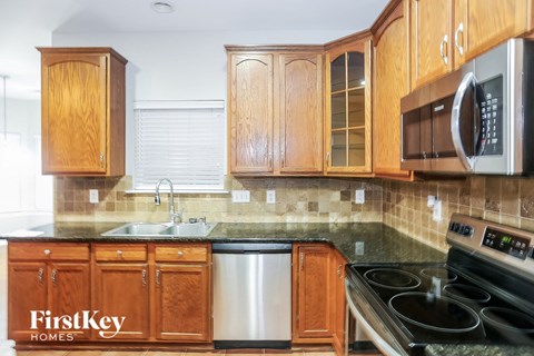 a kitchen with wood cabinets and black countertops and a stainless steel dishwasher