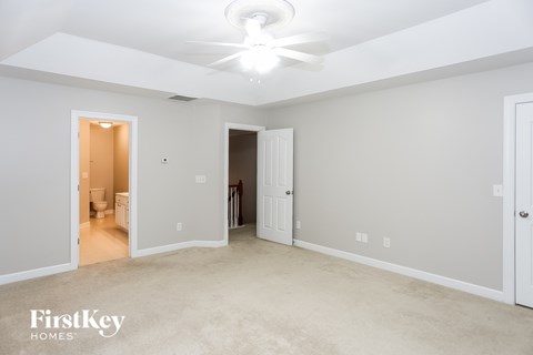 a master bedroom with carpet and a ceiling fan