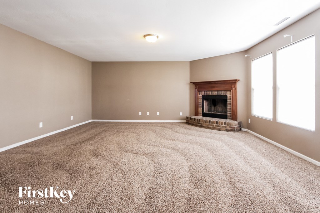 a empty living room with a fireplace and carpet