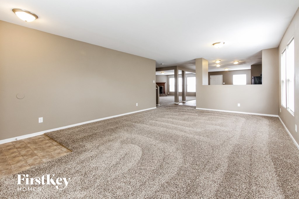 a spacious living room with carpeting and a large room with windows