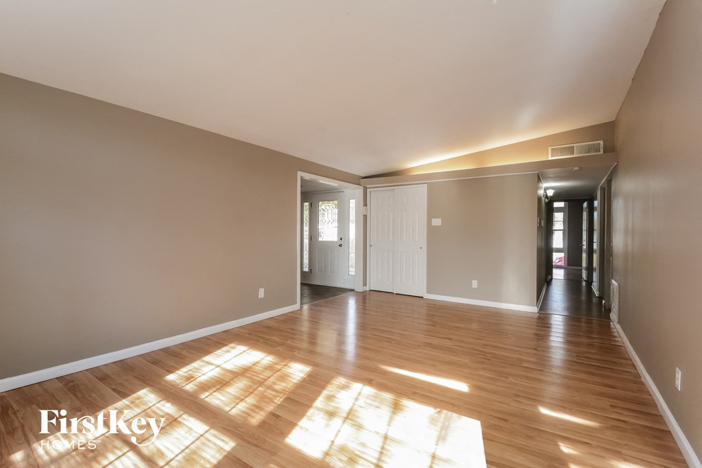 an empty living room with wood floors and a hallway