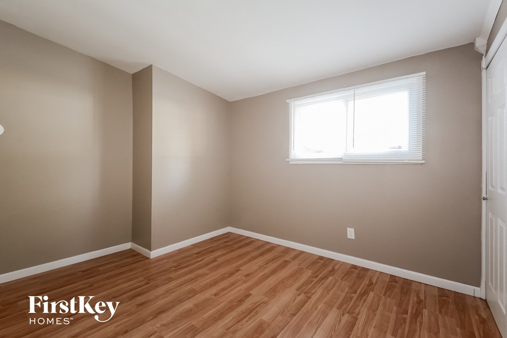 a bedroom with wood flooring and a window