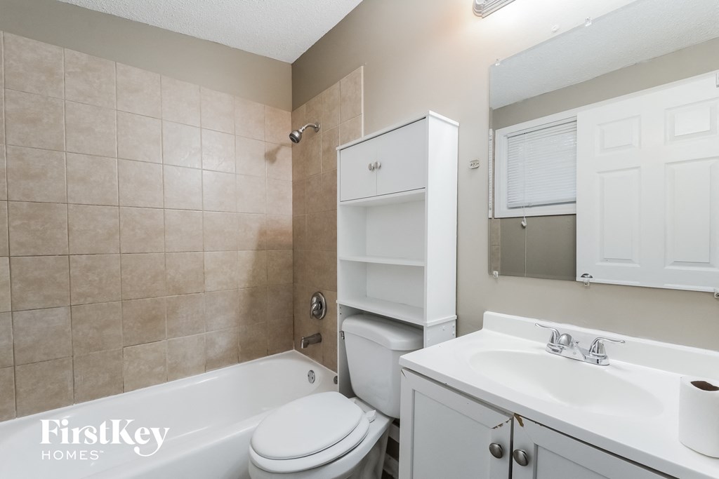a bathroom with a toilet sink and tub and a sink and a mirror