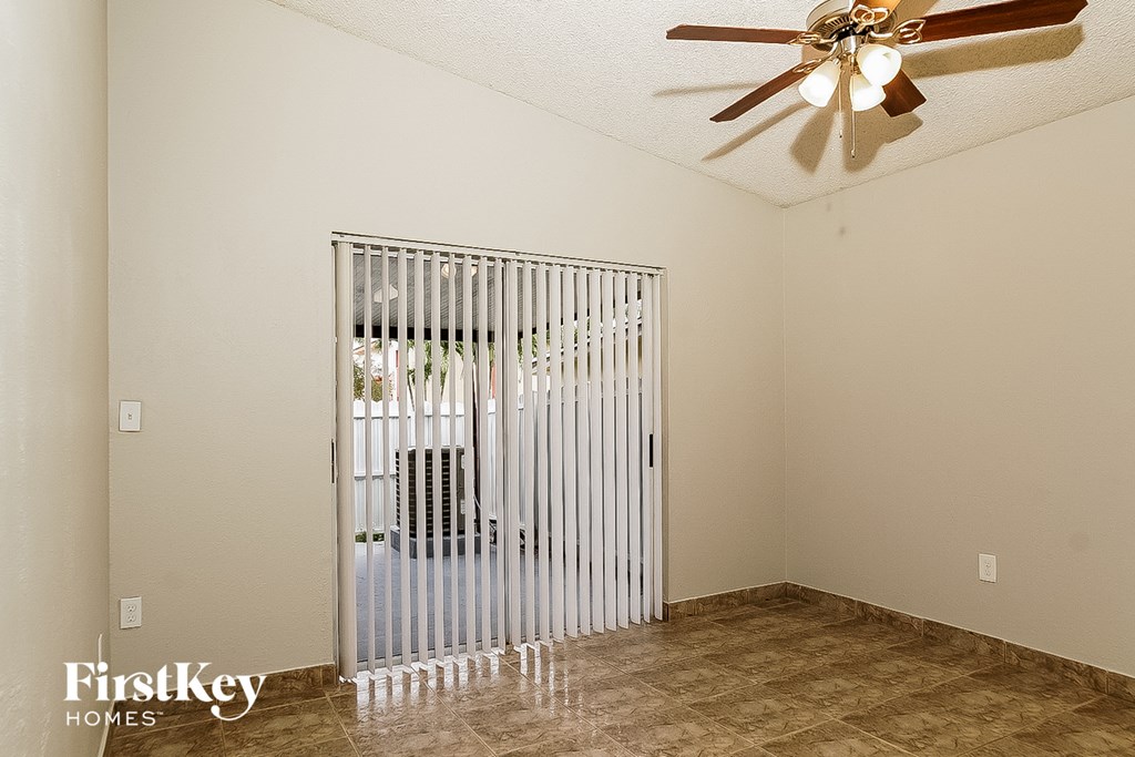 A room with a fan and a sliding door leading to a patio.