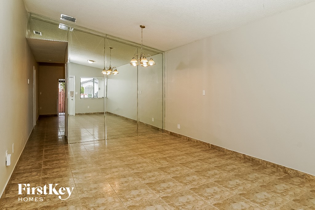 A spacious room with a tiled floor and a glass wall leading to another room.