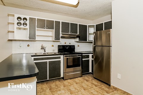 A kitchen with a black counter top and stainless steel appliances.