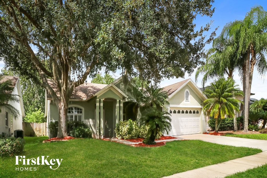 A house with a well-manicured lawn and trees in front of it.