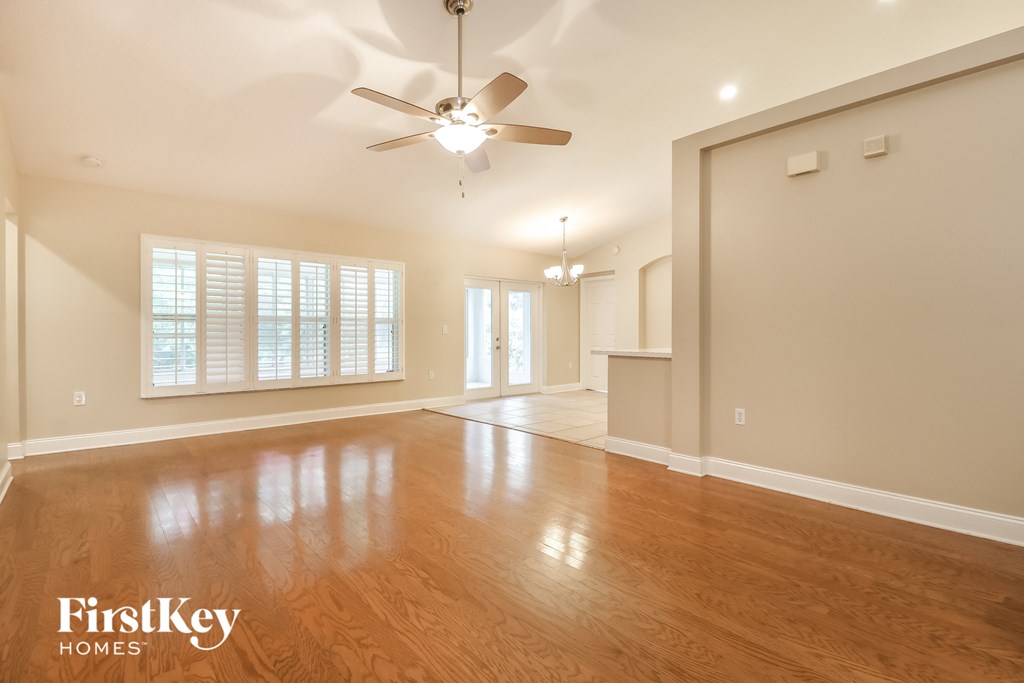 A spacious room with wooden floors and a ceiling fan.