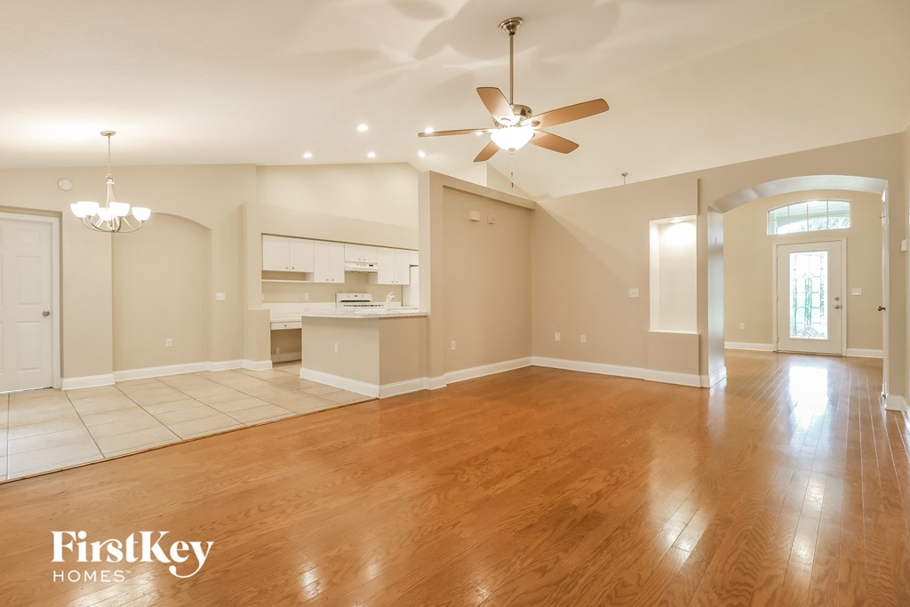 A spacious living room with a ceiling fan and hardwood floors.
