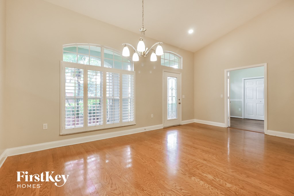 A spacious room with wooden floors and a chandelier.