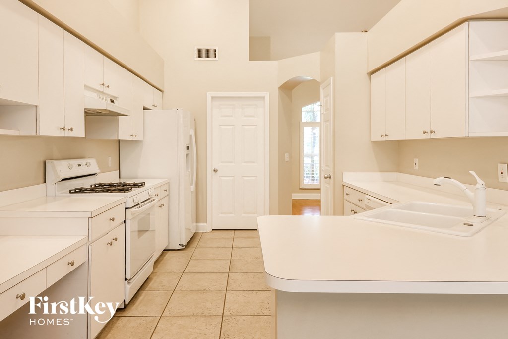 A kitchen with white appliances and cabinets.