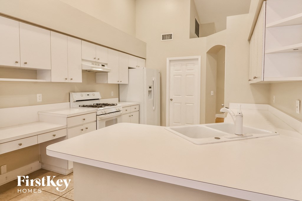 A kitchen with white cabinets and a white sink.