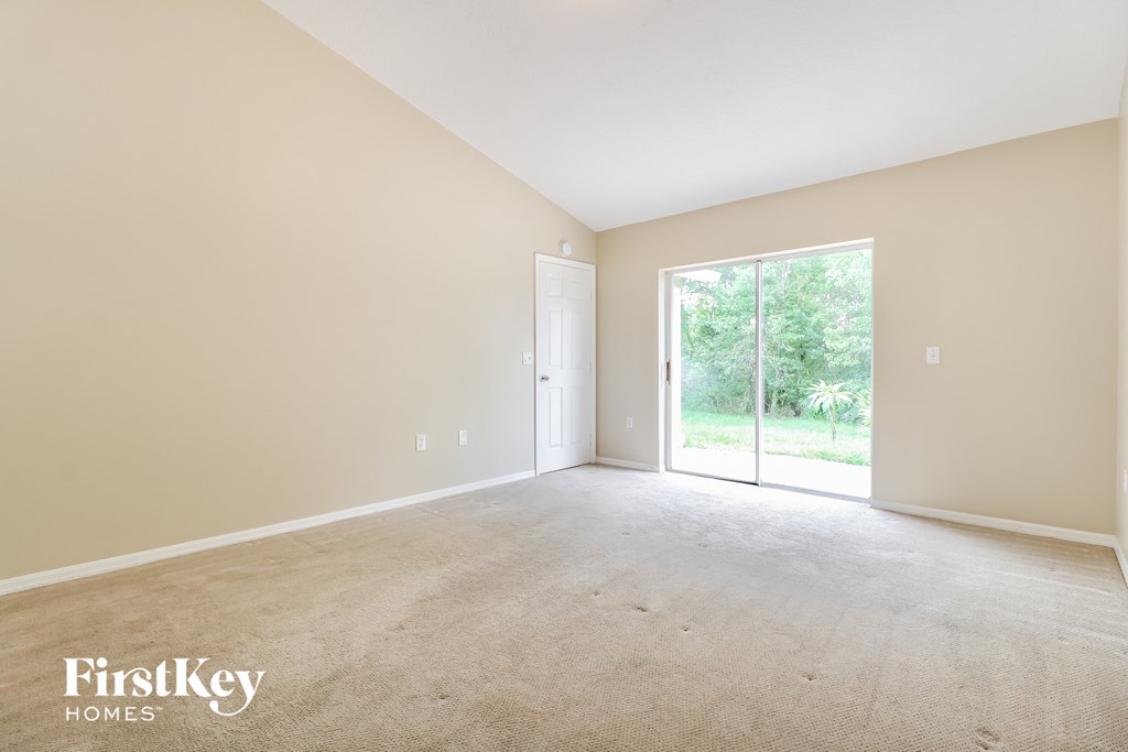A spacious room with a sliding glass door leading to a green outdoor area.