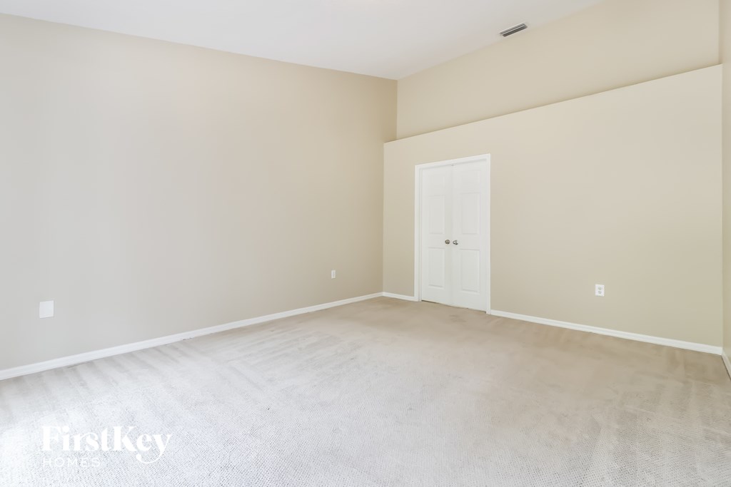 A room with a white door and carpeted floor.