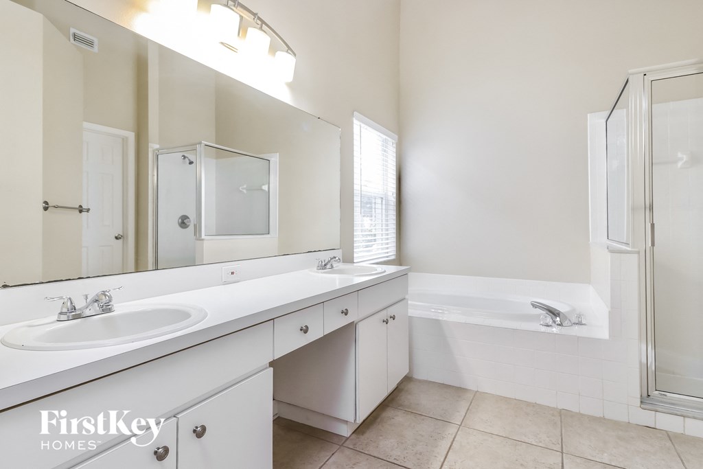 A white bathroom with a double sink and a bathtub.