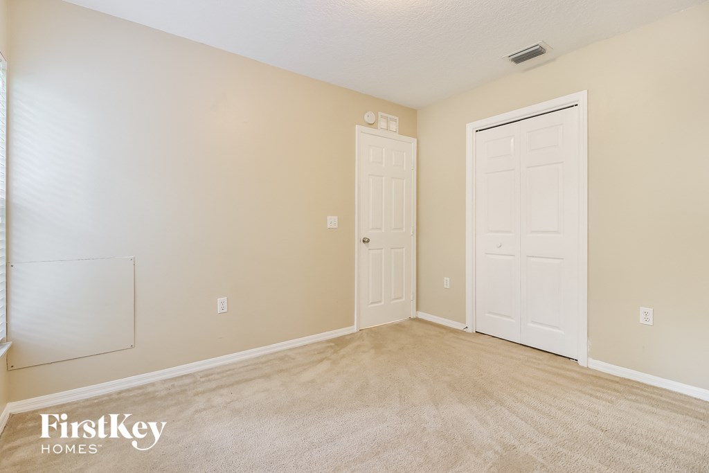A carpeted room with two doors and a window.