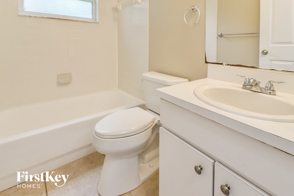 A white toilet in a bathroom with a white tub and sink.