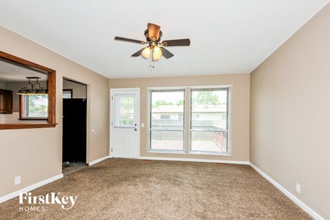 an empty living room with a ceiling fan and a window