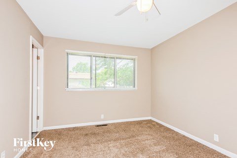 a bedroom with carpet and a window and a ceiling fan